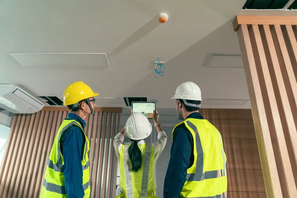 Construction workers inspecting ceiling with tablet indoors