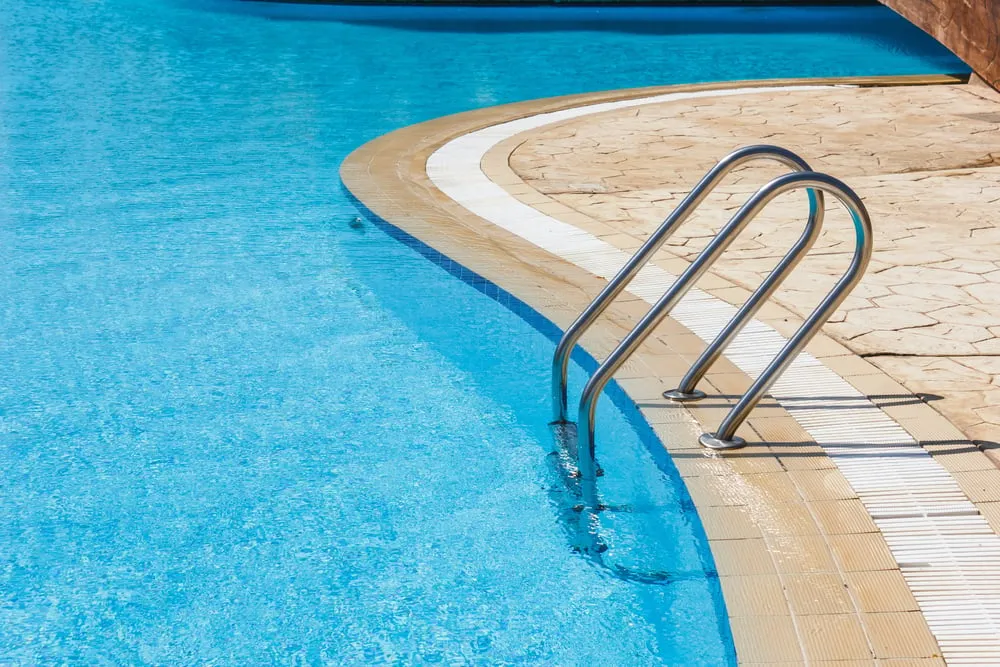Swimming pool with metal ladder and tiled edge