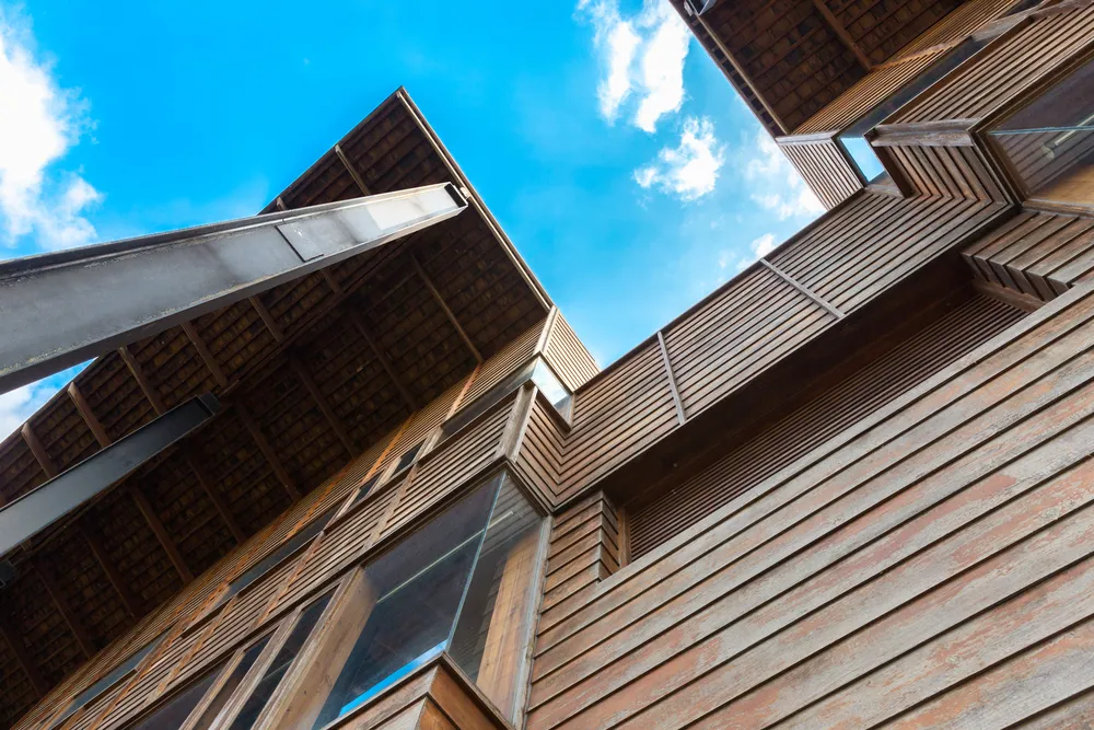 Low-angle view of modern timber-clad building with blue sky