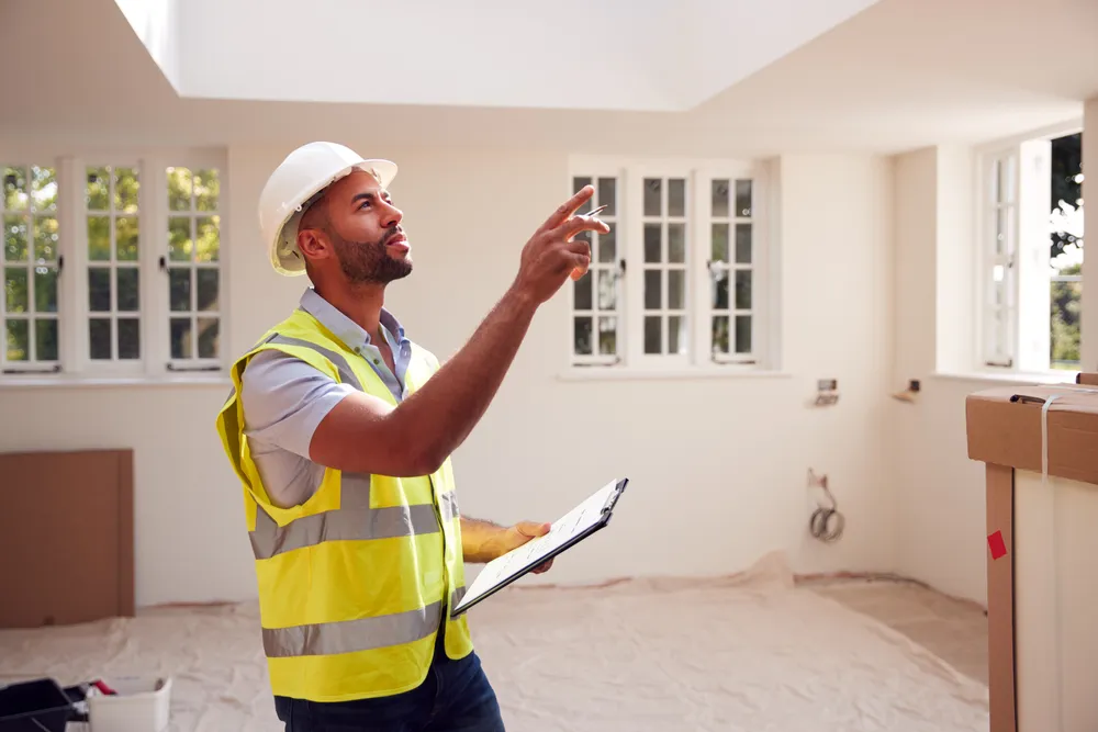 Builder inspecting ceiling in renovated home interior