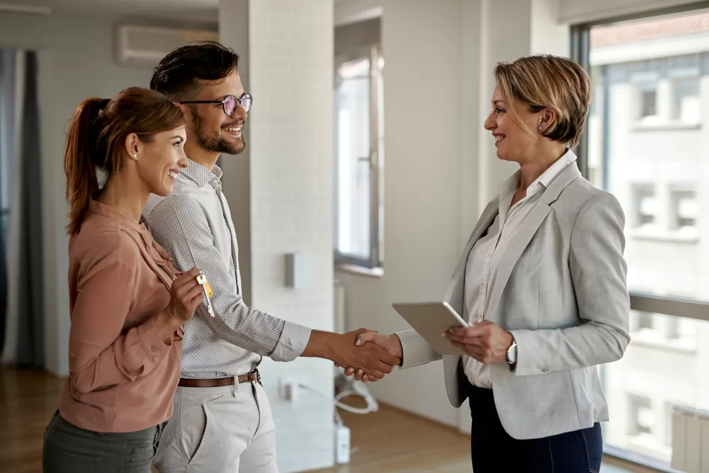 Real estate agent congratulates couple with new house keys