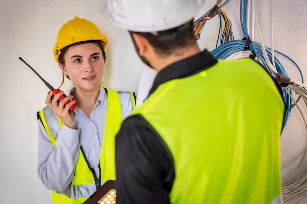 Construction workers discussing wiring with walkie-talkie indoors
