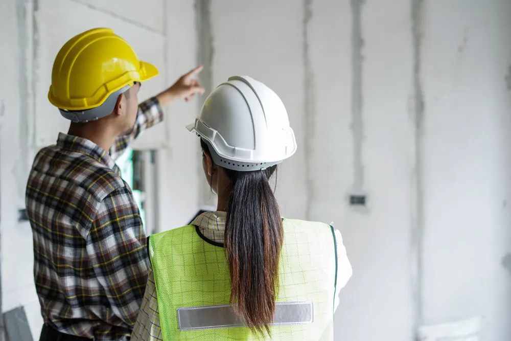 Construction workers inspecting unfinished building interior.
