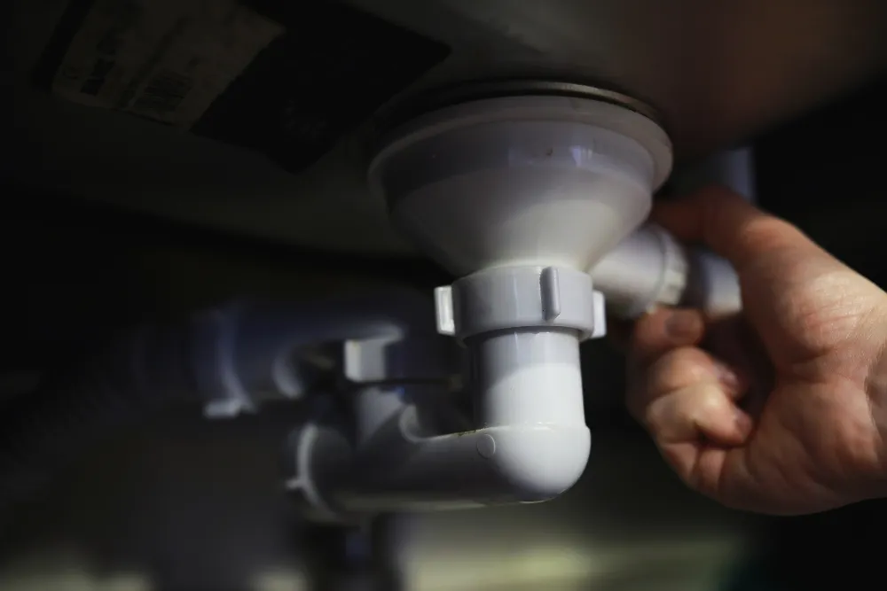 a hand holding the pipe under the sink