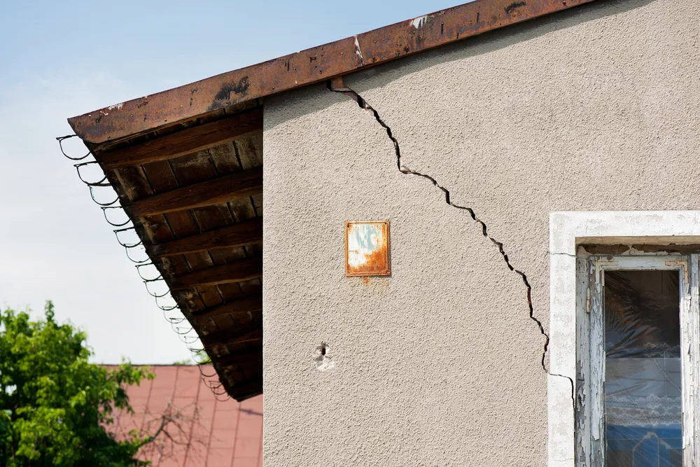 Large crack in exterior house wall near window