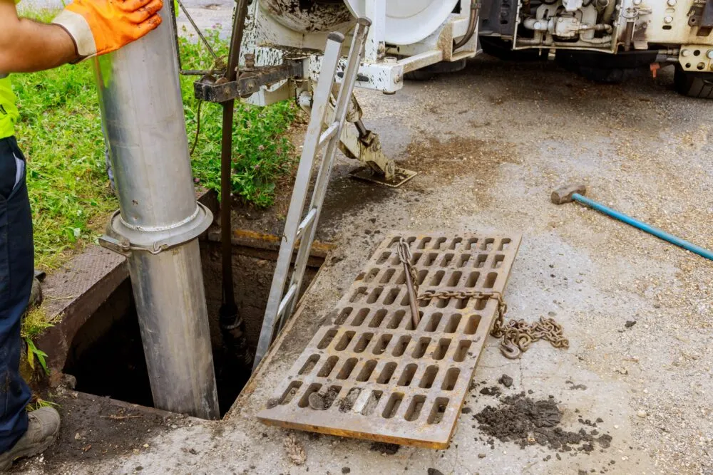 Worker cleaning stormwater drain with vacuum truck hose