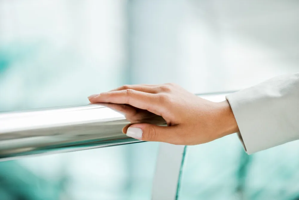 Hand resting on metal railing indoors