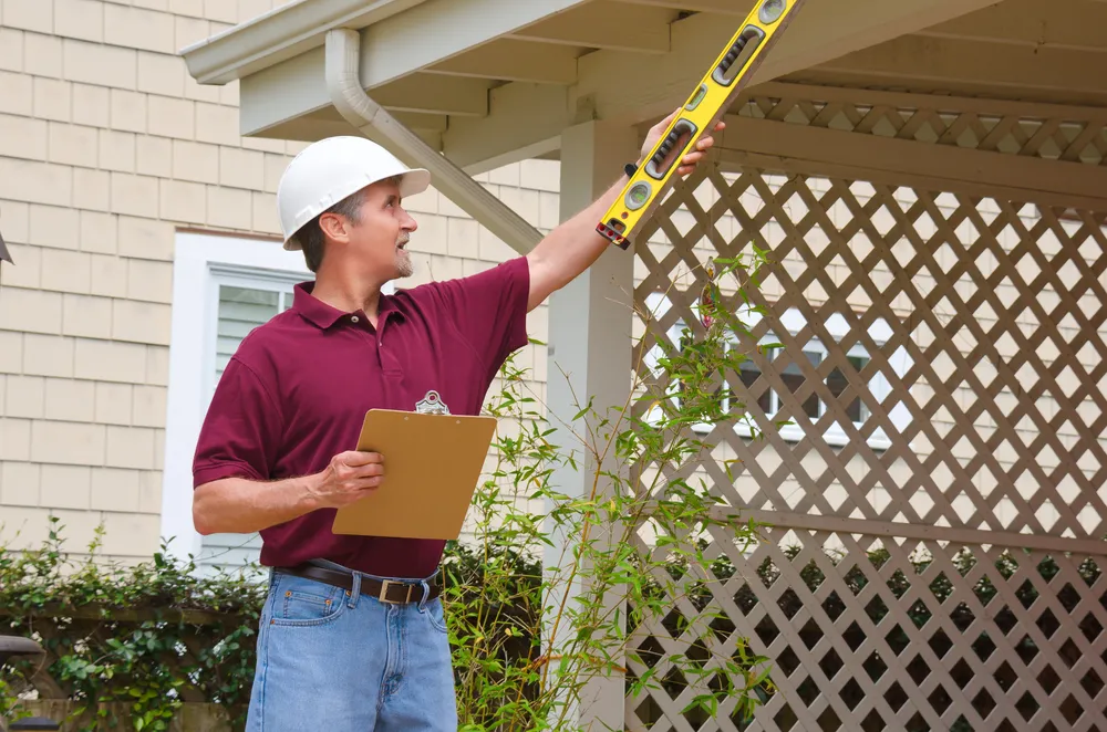 Inspector checking pergola with spirit level and clipboard