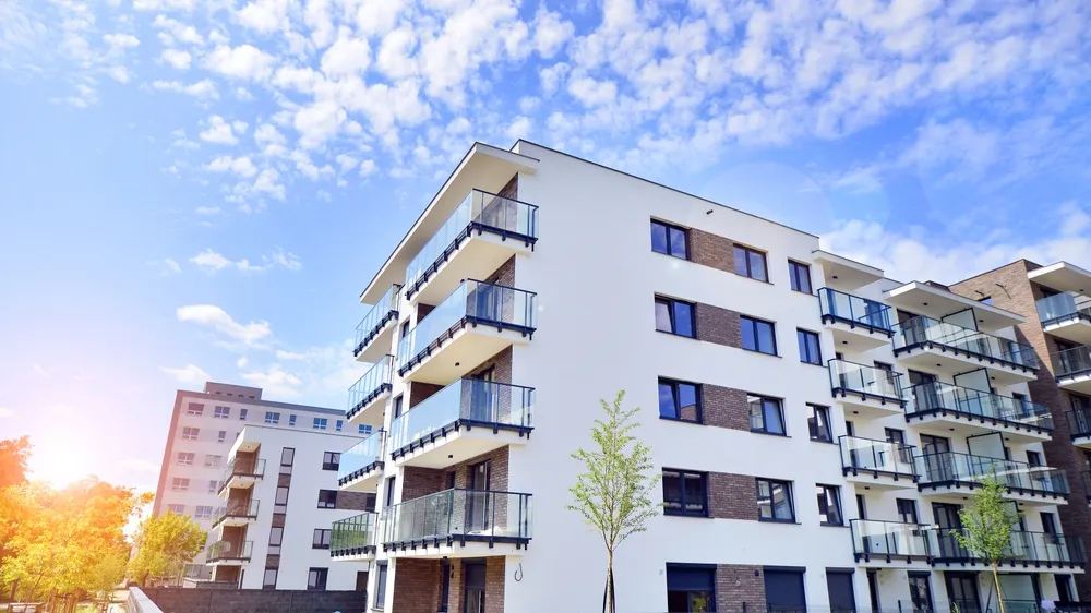 Modern apartment buildings with glass balconies under blue sky