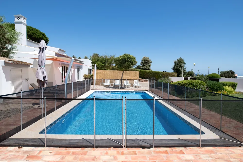 Fenced backyard swimming pool beside modern house