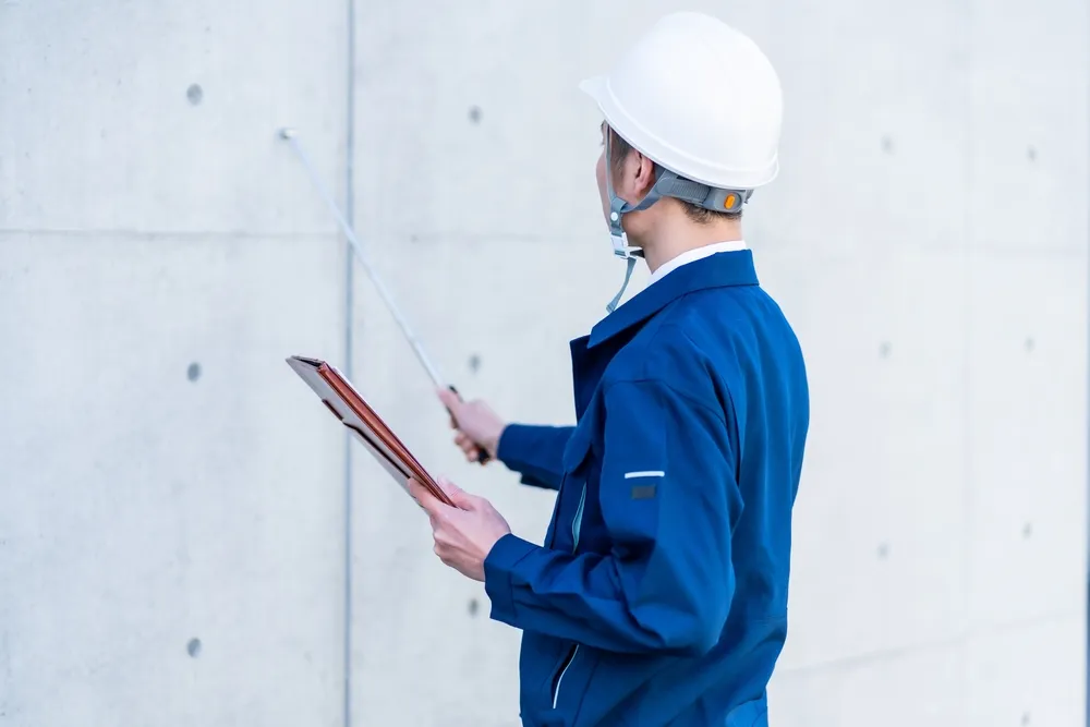 Construction inspector checking concrete wall with clipboard