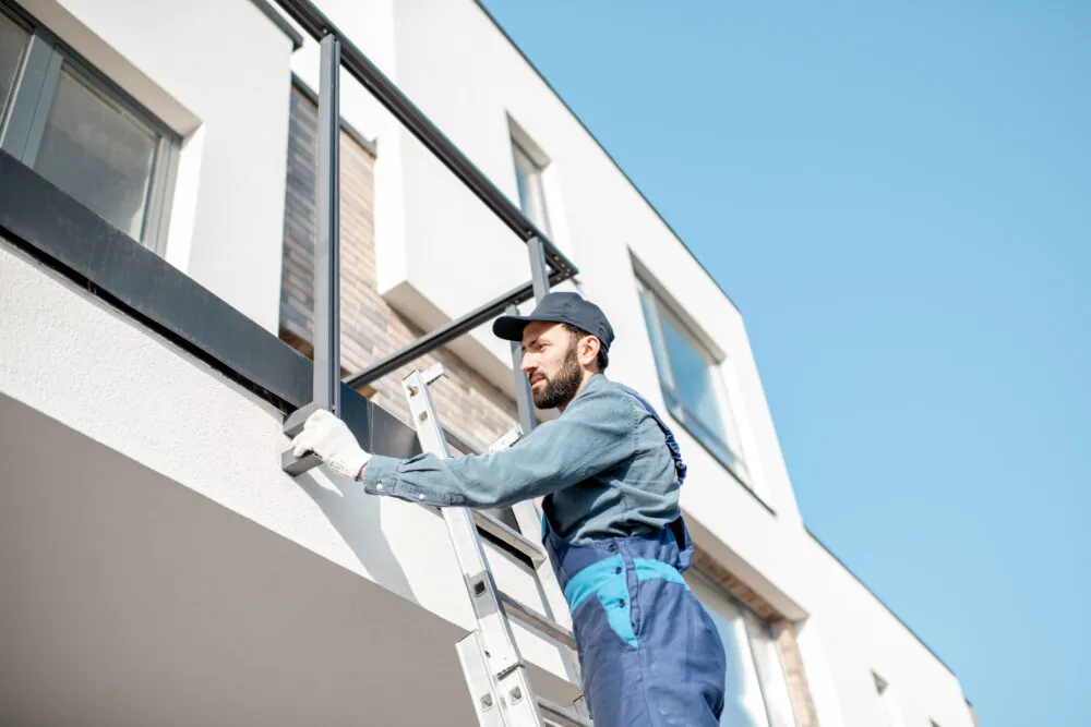 Tradie on ladder fixing balcony railing