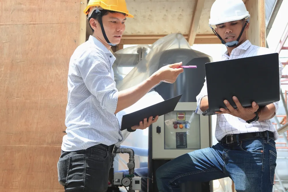 Construction workers reviewing laptop at industrial site