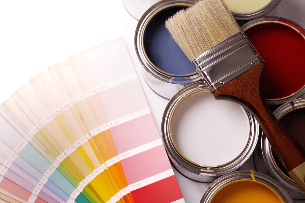 Paint tins, brush and colour swatches on table