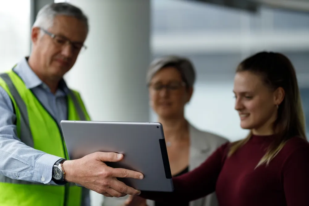 Workers reviewing plans on tablet at site