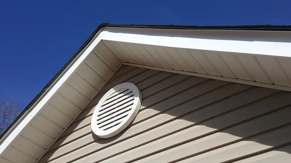 House gable with circular vent under blue sky